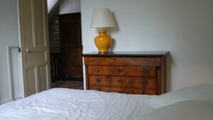 Commode ancienne et lampe dans une chambre d’hôtes du Manoir de Keranflec’h