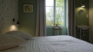 Chambre d’hôtes aux murs verts avec lavabo et fenêtre sur le parc du Manoir de Keranflec’h