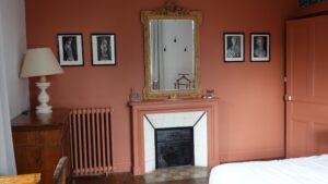 Cheminée, miroir doré et gravures anciennes dans la grande chambre d’hôtes du Manoir de Keranflec’h