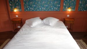 Grande chambre d’hôtes avec lit double, murs terracotta et boiseries fleuries au Manoir de Keranflec’h, près de Brest