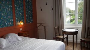 Grande chambre d’hôtes du manoir breton de Keranflec’h avec coin salon et fenêtre sur le domaine