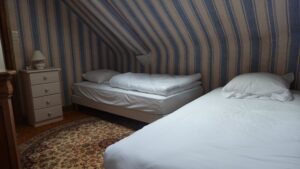 Petite chambre avec deux lits simples et papier peint rayé au Manoir de Keranflec’h