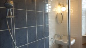 Douche au carrelage bleu dans une salle d’eau du Manoir de Keranflec’h